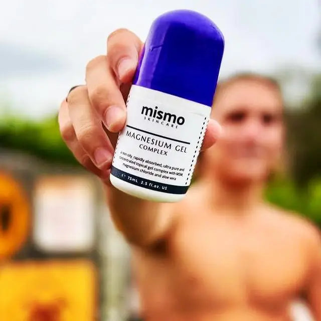 Person holding a bottle of 'mismo' magnesium gel complex with a blurred background