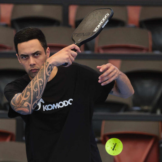 Matt Carter hitting Bioball with a Tenet pickleball paddle with 'Komodo' branding in an indoor setting.