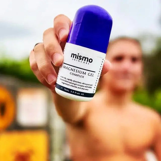 Person holding a bottle of 'mismo' magnesium gel complex with a blurred background
